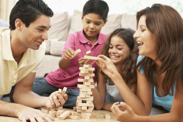 Family playing a game of Jenga together at home.