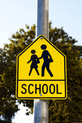 Bright yellow school zone sign representing safety and stability for foster children attending school.