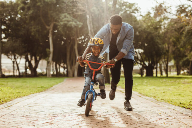 Foster Dad teaching foster child how to ride a bike