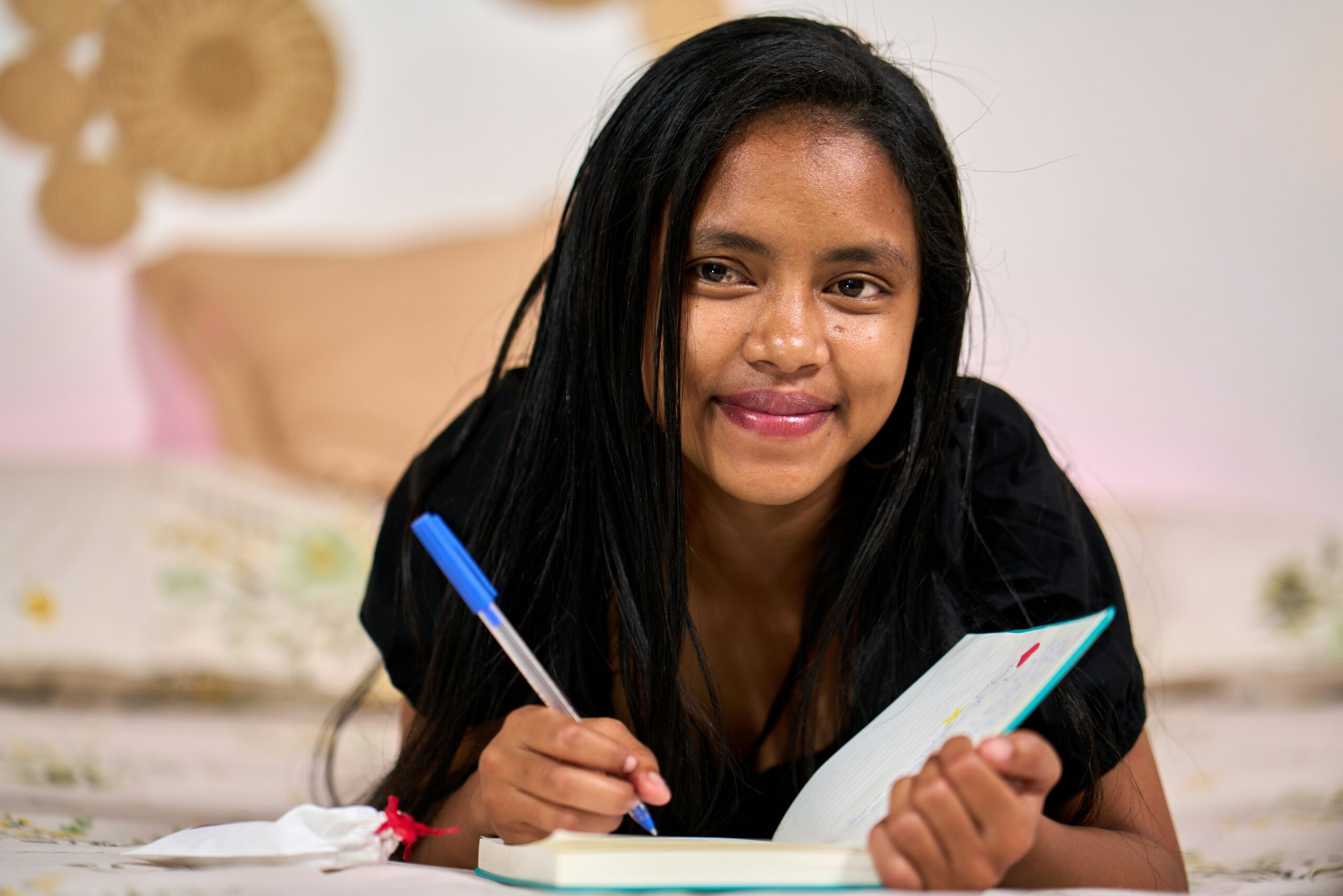Girl sitting on the floor writing in a notebook
